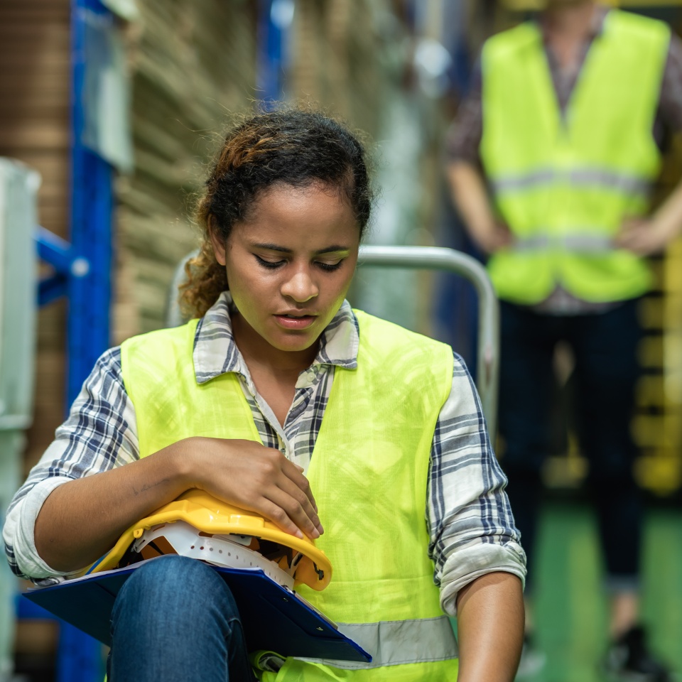 Young African female warehouse worker staff feeling sad and upset while sitting on the floor of the storehouse due to been fired from job cause by company bankruptcy from coronavirus pandemic.