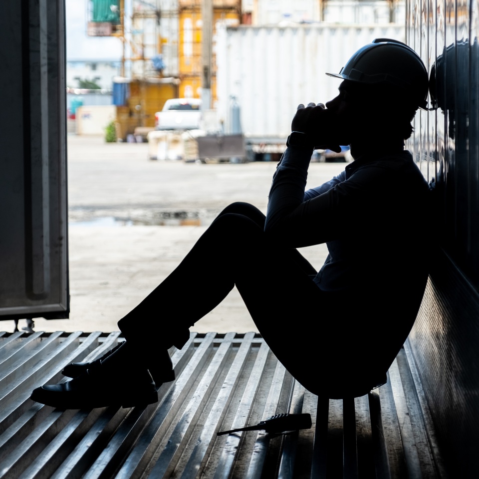 Depressed and tried foreman or businessman sitting inside the container in shipyard logistic factory because losing his job or fired because of mistake. Worker or officer feeling sad and depressed.