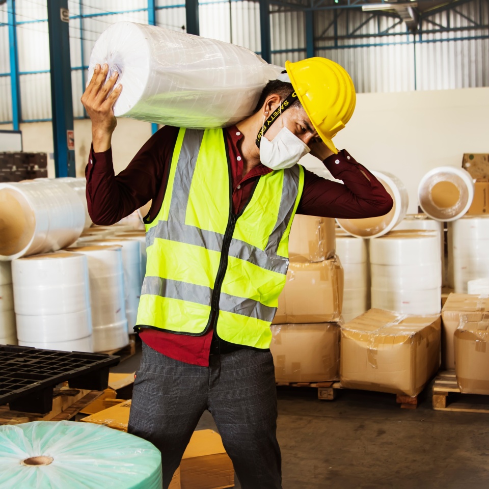 Male workers carry heavy rolls of fabric over their shoulders to move them into production and are at risk of injury from lifting too heavy loads many times without weight-lifting equipment.