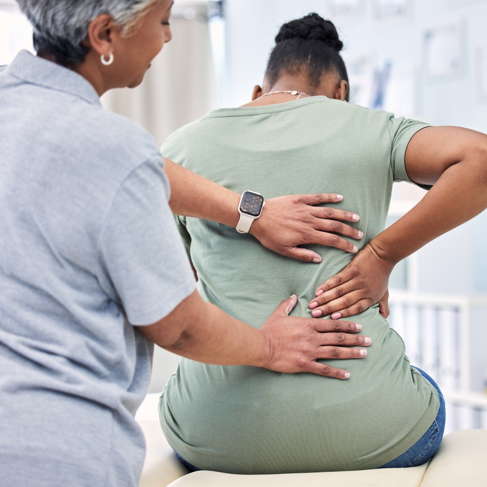 Back pain, physical therapy and chiropractor with patient, spine injury and healthcare with help and people at clinic. Physiotherapy, massage and anatomy with body, support and trust in health