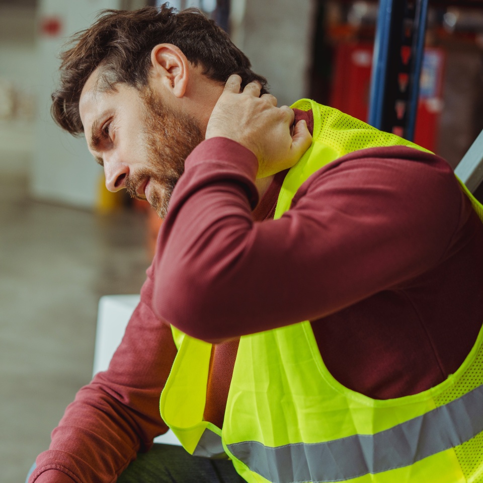 Tired, upset, sick bearded man, worker having neck and back pain, after work in warehouse, copy space. Concept of health care, treatment