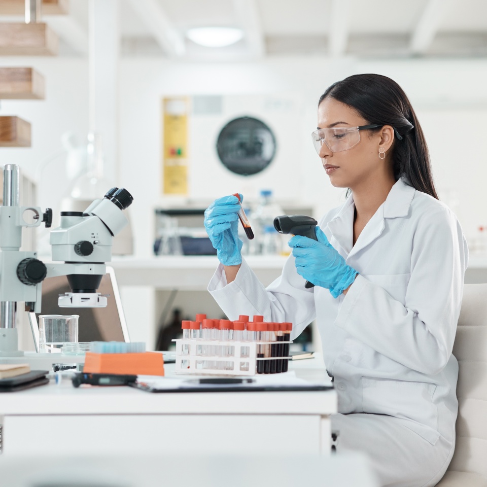 Science, blood sample and microscope research for DNA study with virus analysis with vial. Woman, scientist and ppe for protection with medical test and experiment for forensic laboratory work